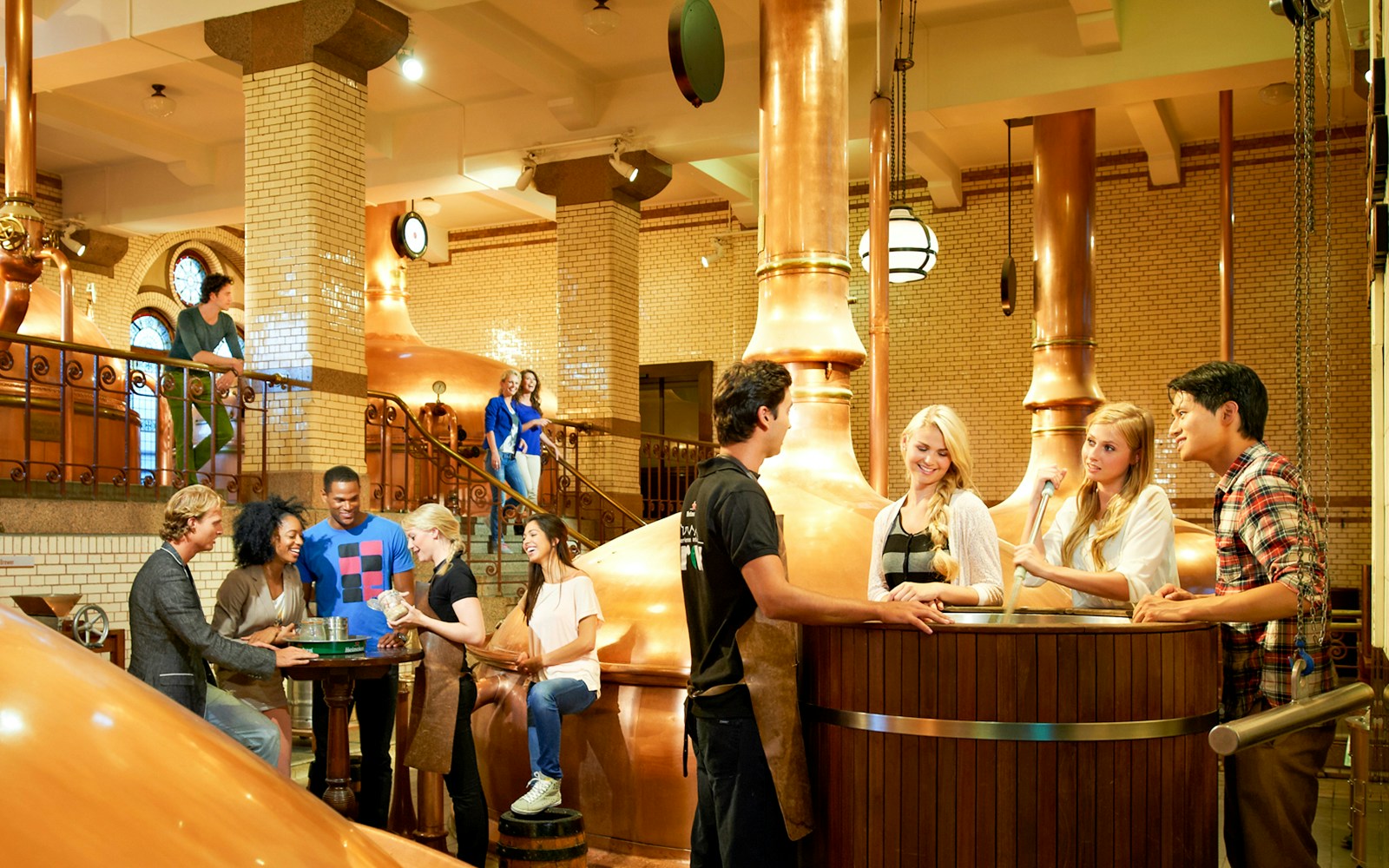Visitors exploring Heineken brewery in Amsterdam with drinks in hand.