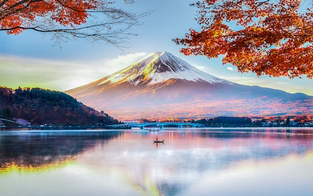 Mount Fuji reflected in Lake Kawaguchi with autumn leaves in the foreground.