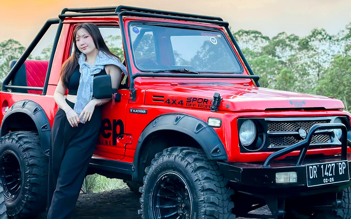 Red Jeep for Mount Batur Sunrise Tour with forest backdrop.