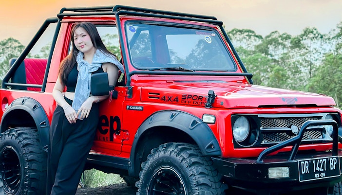 Red Jeep for Mount Batur Sunrise Tour with forest backdrop.