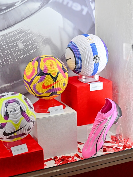 Display of football memorabilia at Liverpool FC Museum, Anfield, featuring balls and boots.