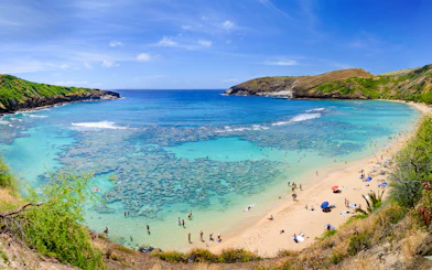 Aerial view of Hanauma Bay, Hawaii, with people on the sandy shore and clear blue water.