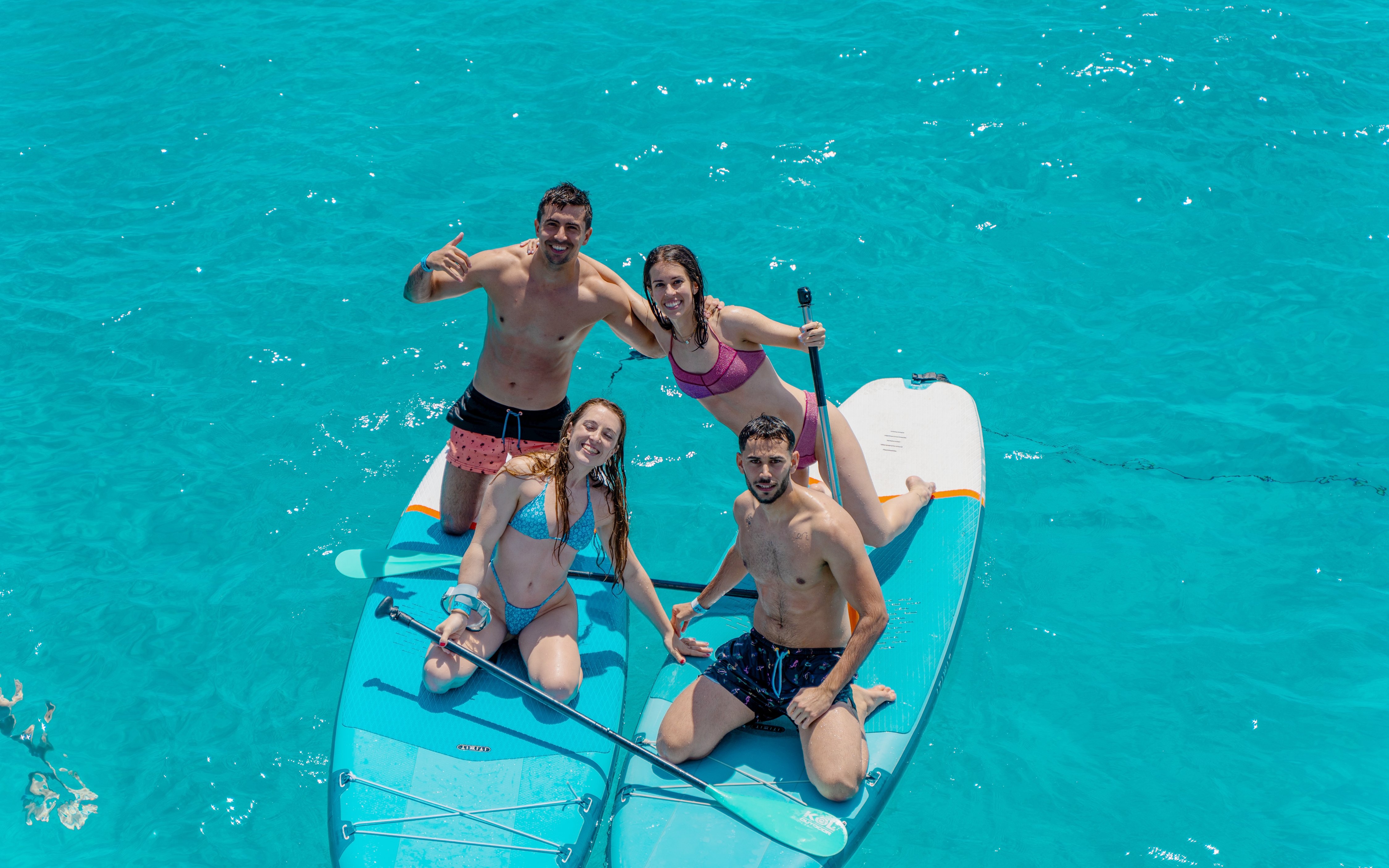 Friends paddleboarding on clear blue water during Formentera Cruise Tour.