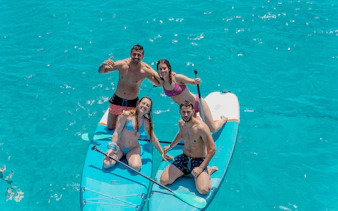 Friends paddleboarding on clear blue water during Formentera Cruise Tour.