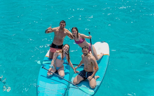 Friends paddleboarding on clear blue water during Formentera Cruise Tour.