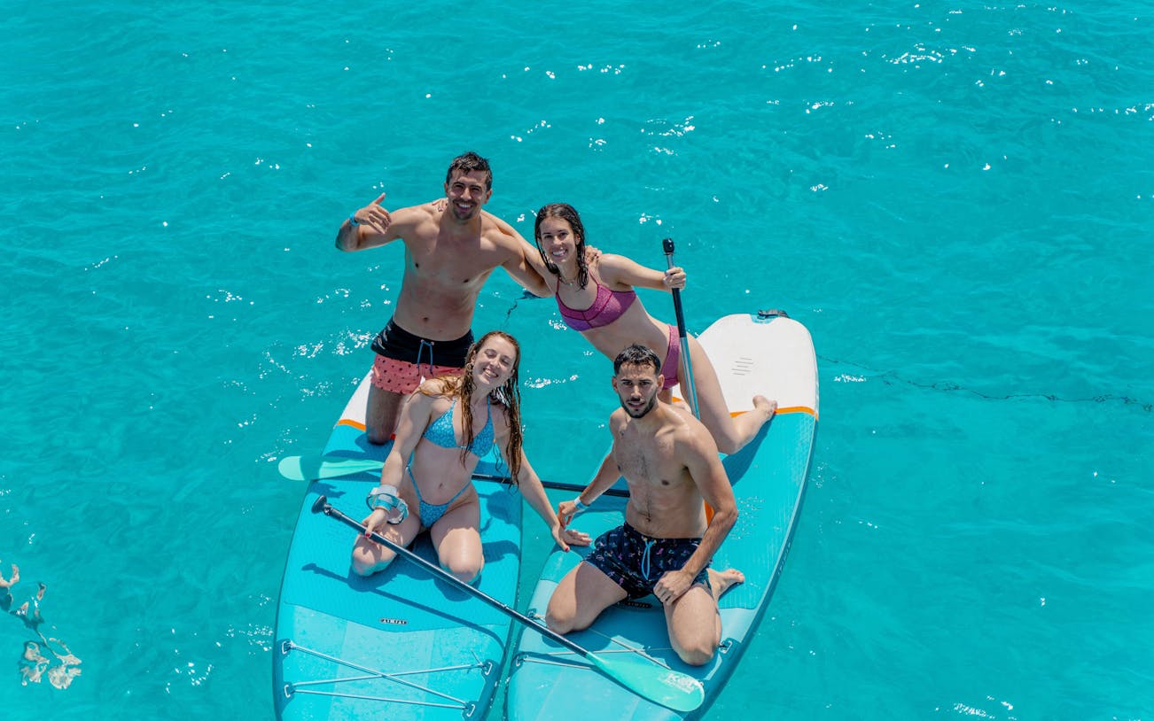 Friends paddleboarding on clear blue water during Formentera Cruise Tour.