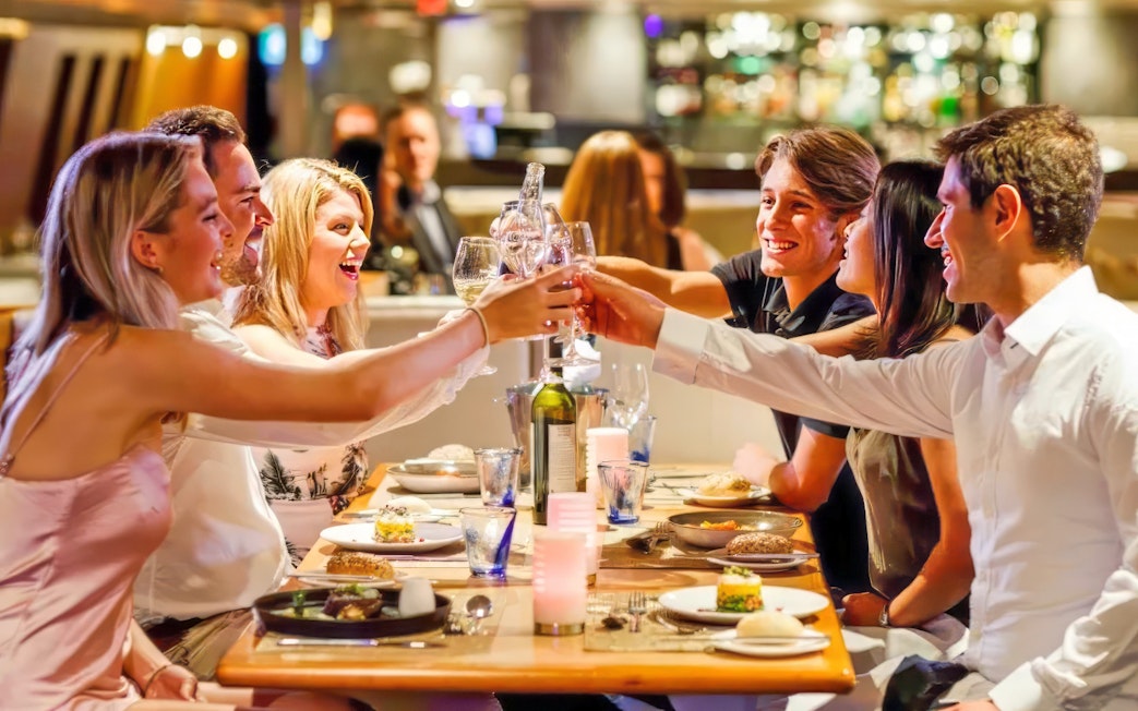 Group toasting at dinner table on Starlight Dinner Cruise in Sydney.