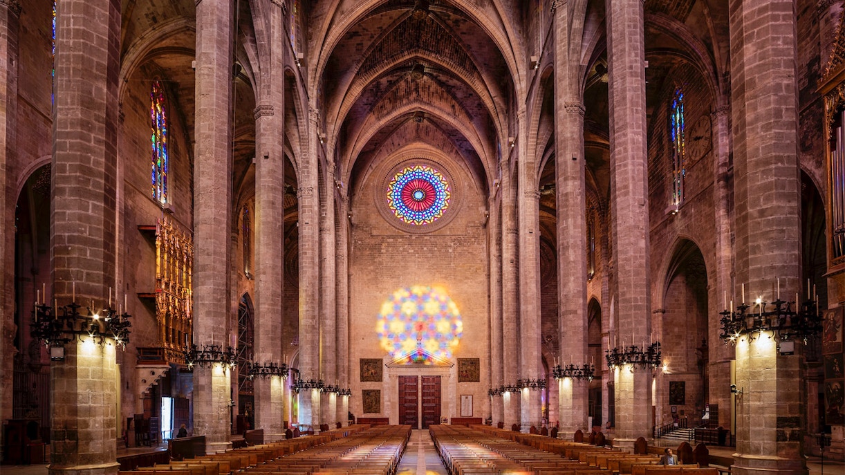 Visitors inside Palma Cathedral exploring its Gothic architecture and stained glass windows in Palma, Spain