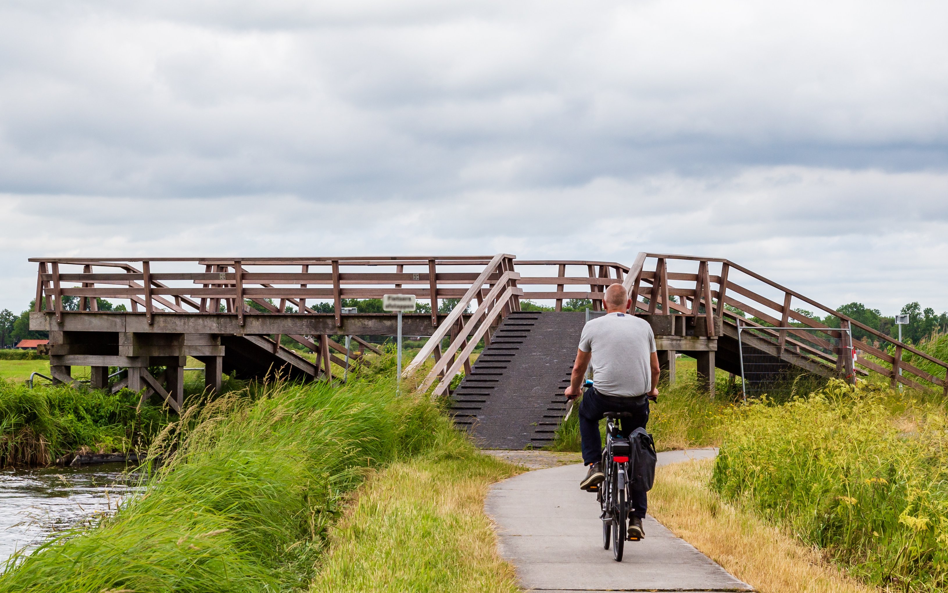 Cyclist crossing wooden bridge in Nationaal Park Weerribben-Wieden, Sint Jansklooster, Netherlands.
