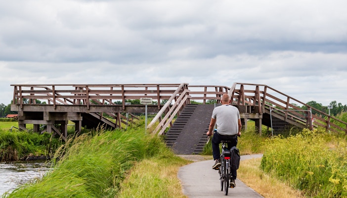 Cyclist crossing wooden bridge in Nationaal Park Weerribben-Wieden, Sint Jansklooster, Netherlands.
