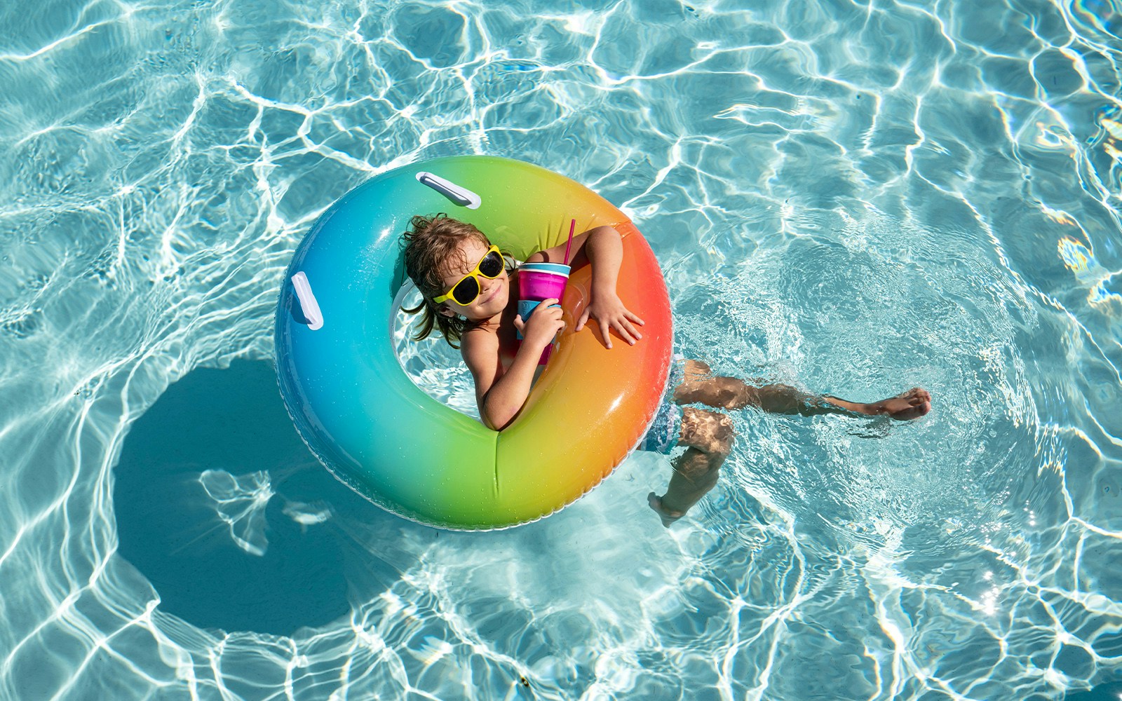 Child relaxing in a pool on a rainbow float at Aqualand.