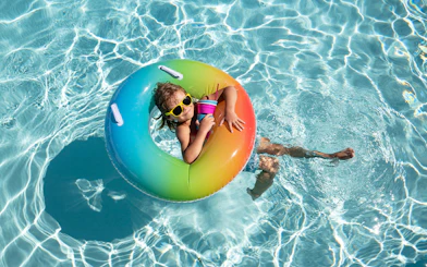 Child relaxing in a pool on a rainbow float at Aqualand.