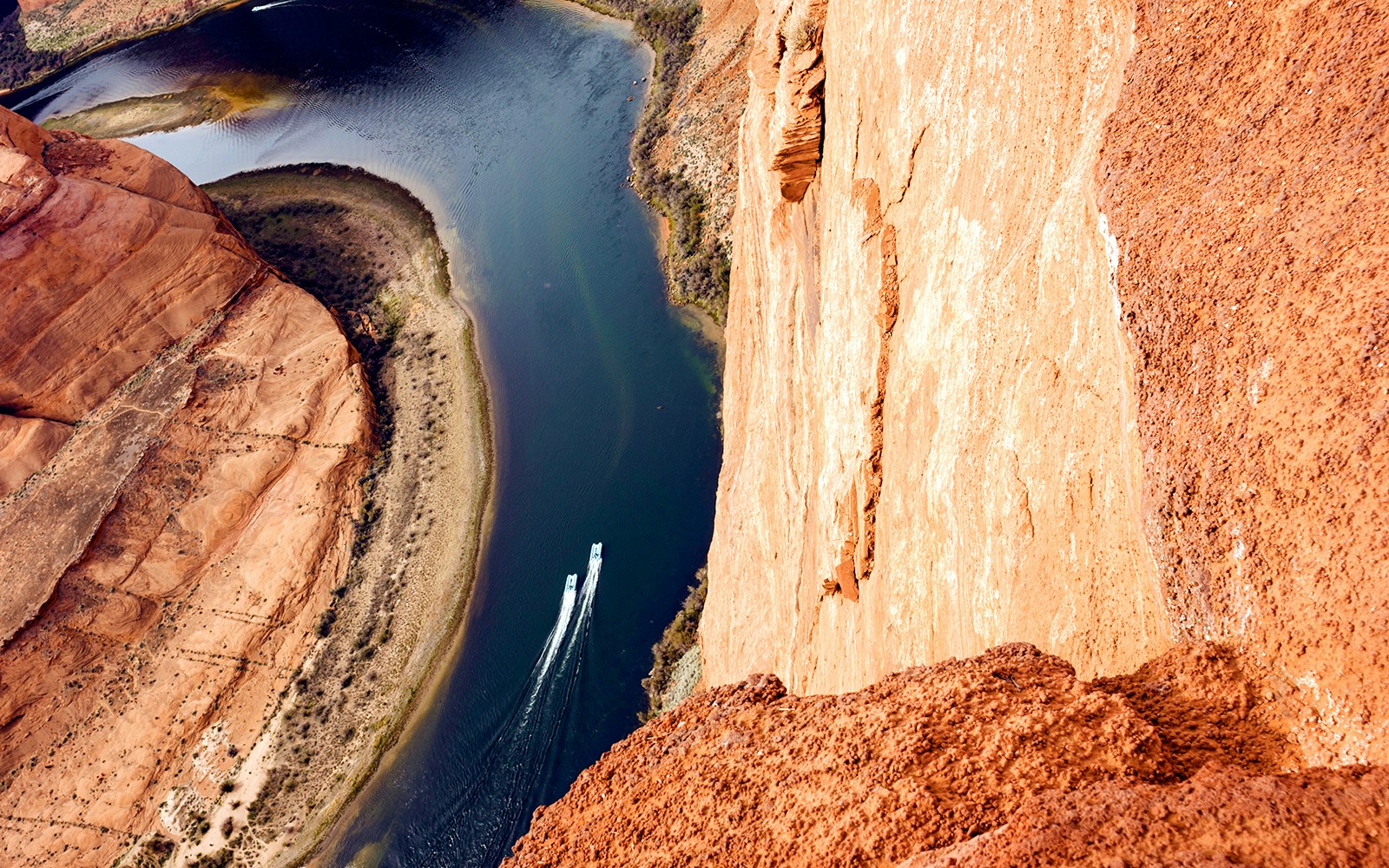 Two boats on Colorado River at Horseshoe Bend, deep canyon walls surrounding.