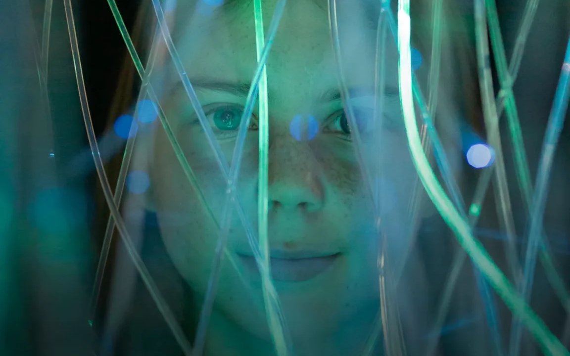 Person surrounded by glowing fiber optics at an interactive exhibit in an epic museum.