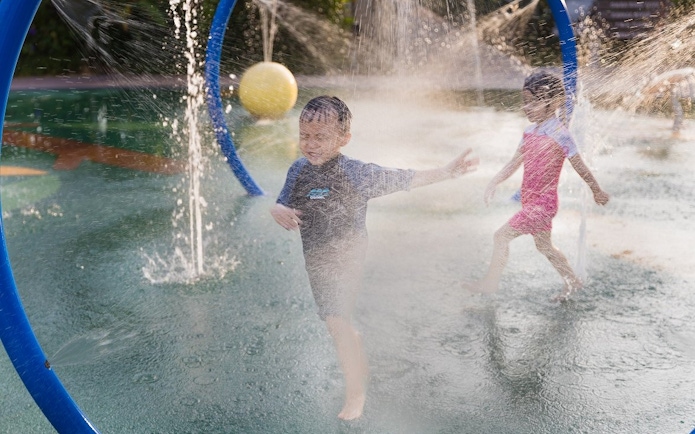 Children playing in water sprays at SplashMania Waterpark during Night Splash event.