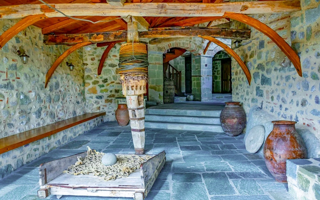 Monastery of the Holy Trinity at Meteora interior with stone walls and wooden beams.