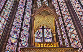 Stained glass windows inside Sainte Chapelle, Paris, showcasing intricate biblical scenes.