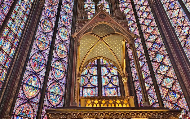 Stained glass windows inside Sainte Chapelle, Paris, showcasing intricate biblical scenes.