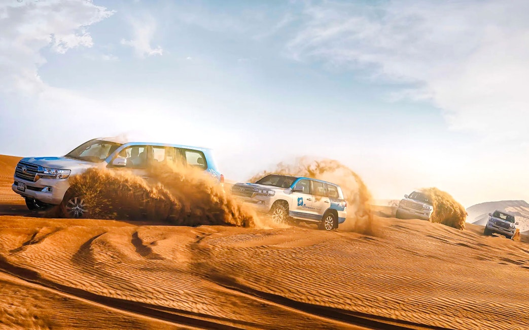 SUVs driving through sand dunes during Abu Dhabi desert safari.
