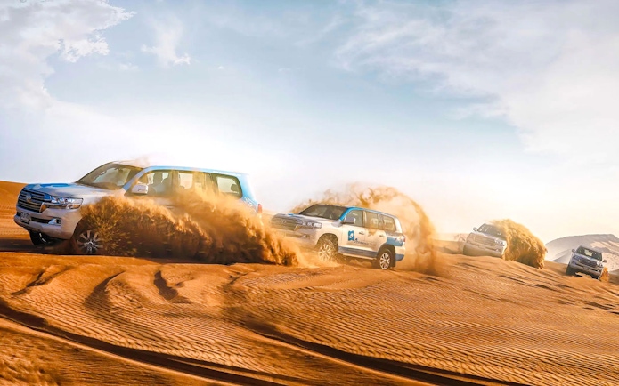 SUVs driving through sand dunes during Abu Dhabi desert safari.