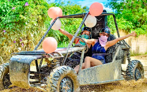 Two people driving a buggy through muddy trails in Punta Cana.
