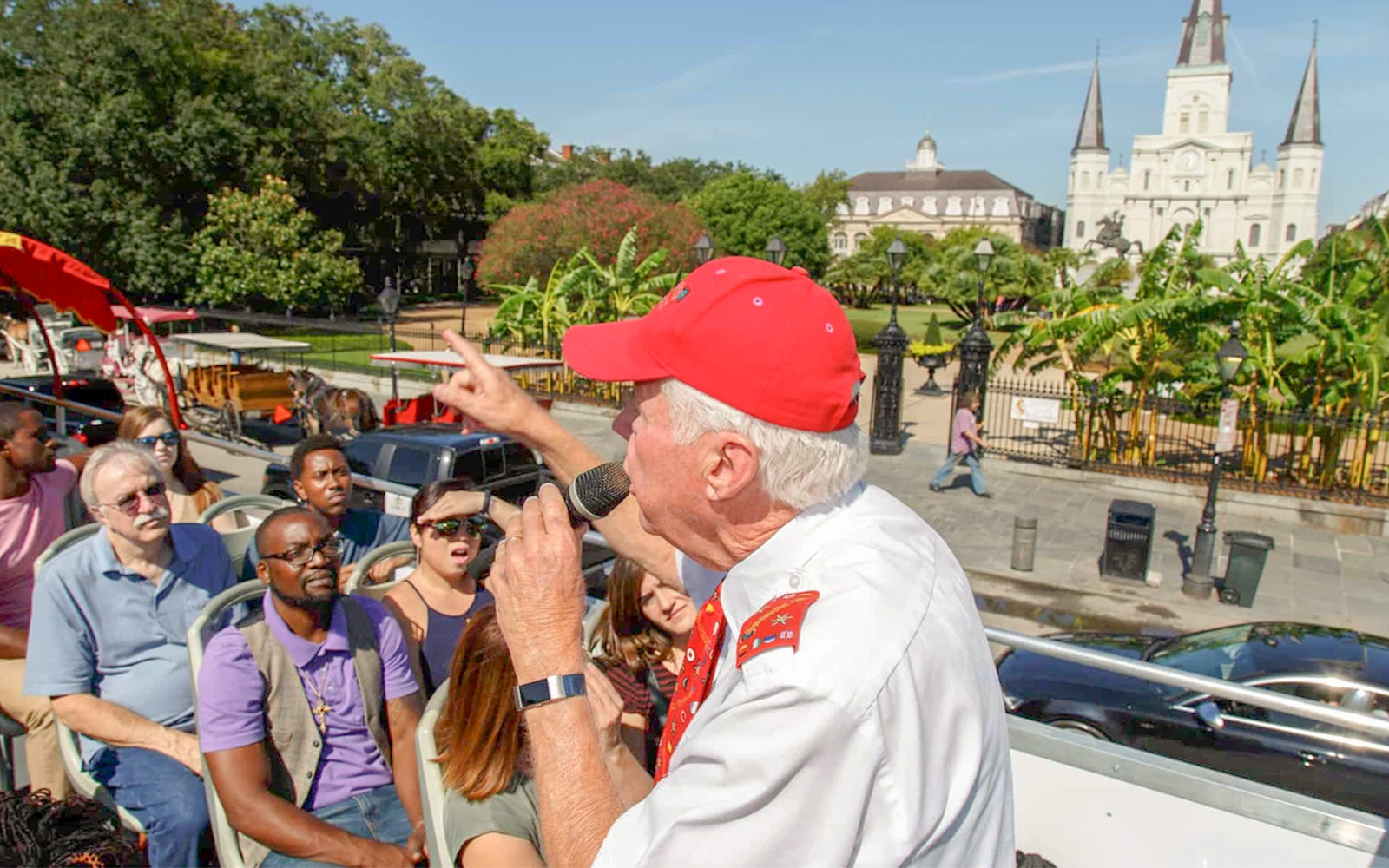 Double-decker bus on New Orleans Hop-On Hop-Off tour passing historic French Quarter buildings.