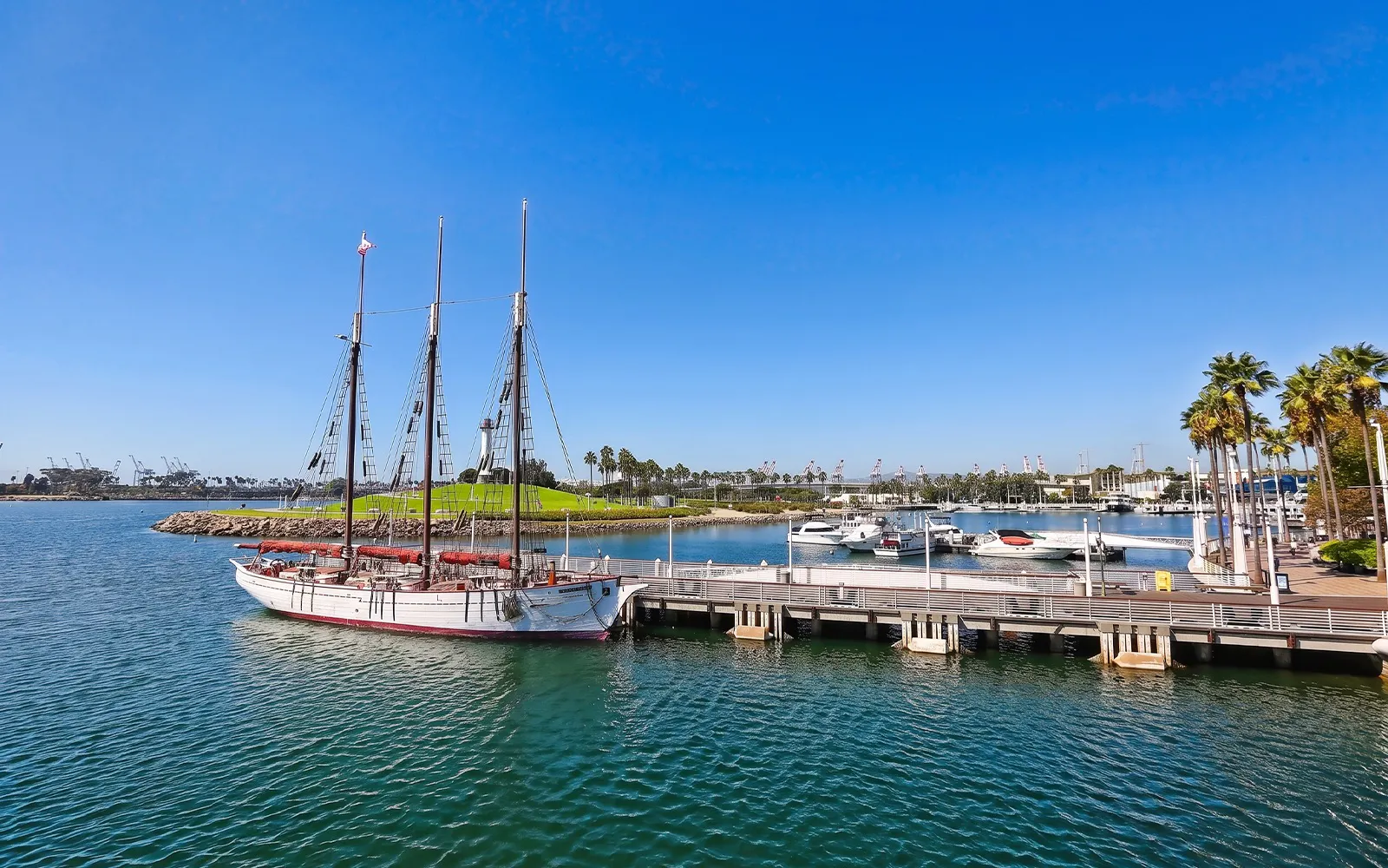 Sailing ship docked at Long Beach harbor with palm trees and marina views.