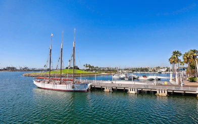 Sailing ship docked at Long Beach harbor with palm trees and marina views.