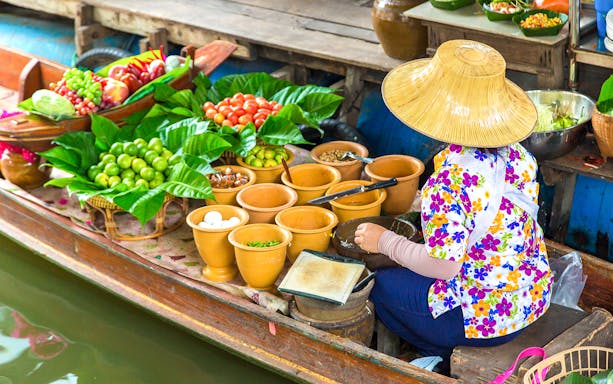 Vendor selling fruits and vegetables from a boat at Pattaya Floating Market.