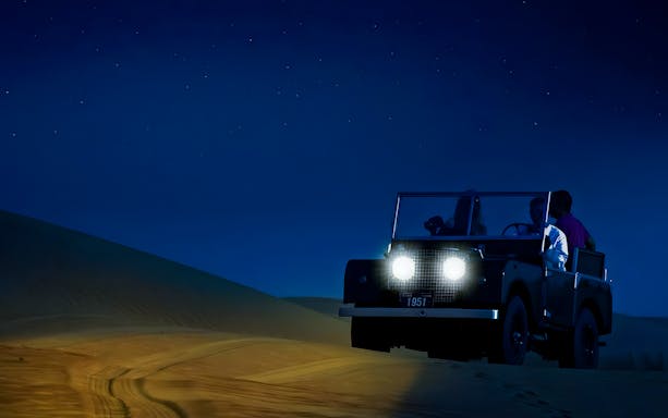 Off-road vehicle on a desert night safari under a starry sky.