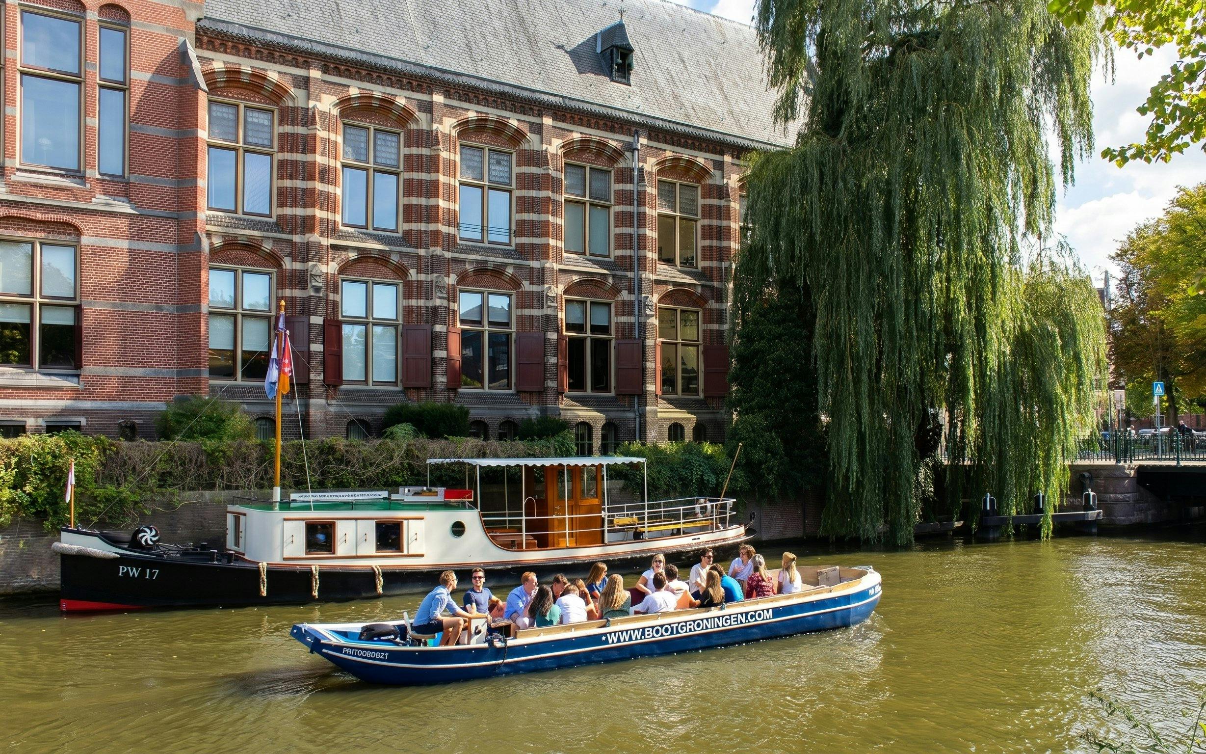 Groningen canal cruise boat with tourists passing historic brick building.