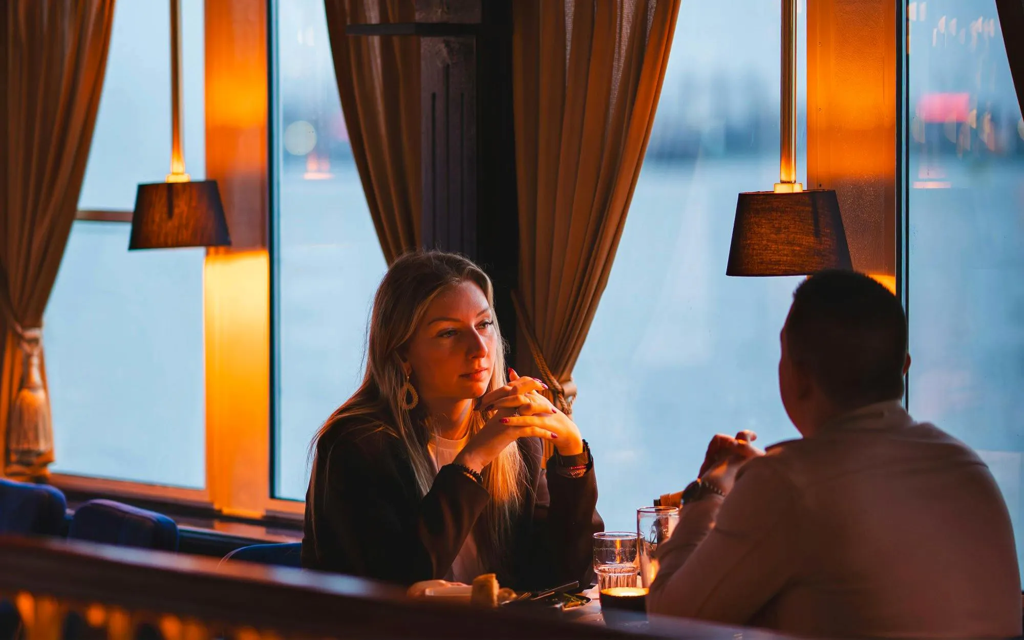Couple dining on a pizza cruise with scenic window view.