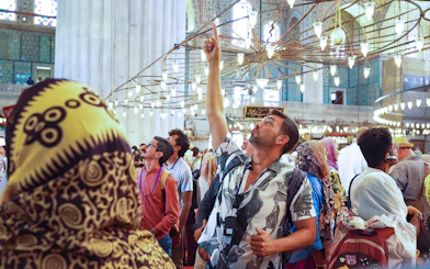 Tourists inside Istanbul's Blue Mosque during a guided tour, admiring the ornate ceiling.
