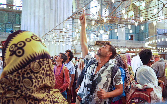 Tourists inside Istanbul's Blue Mosque during a guided tour, admiring the ornate ceiling.