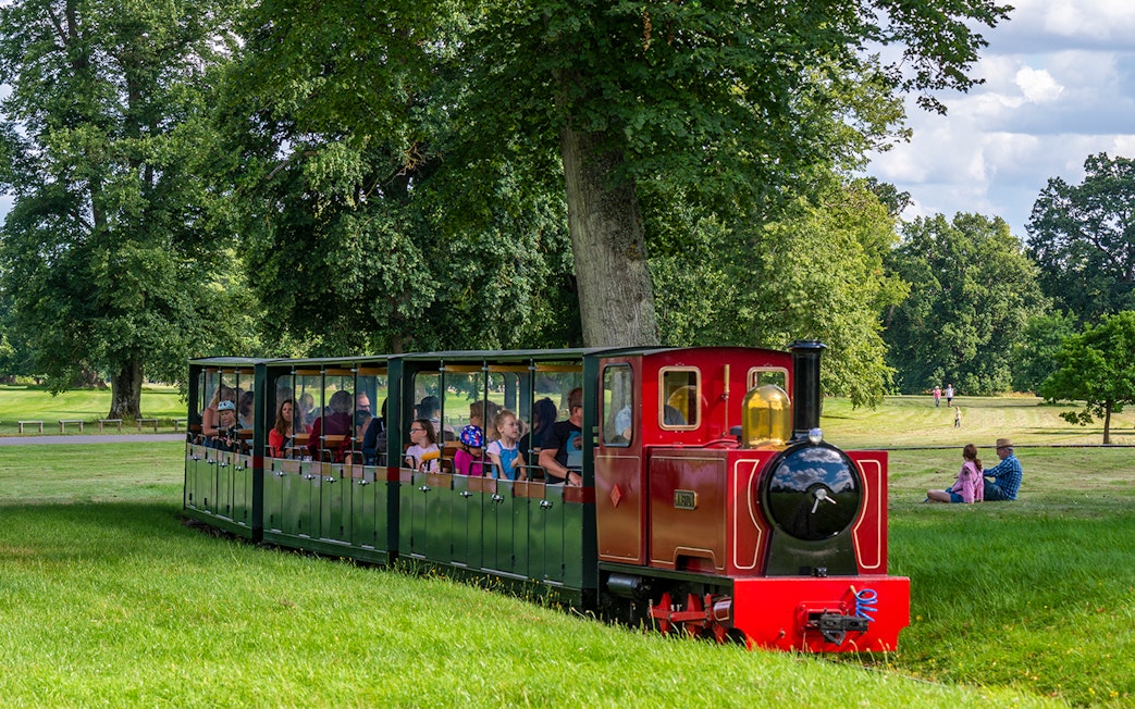 Toy train ride at Blenheim Palace with passengers enjoying the scenic park view.