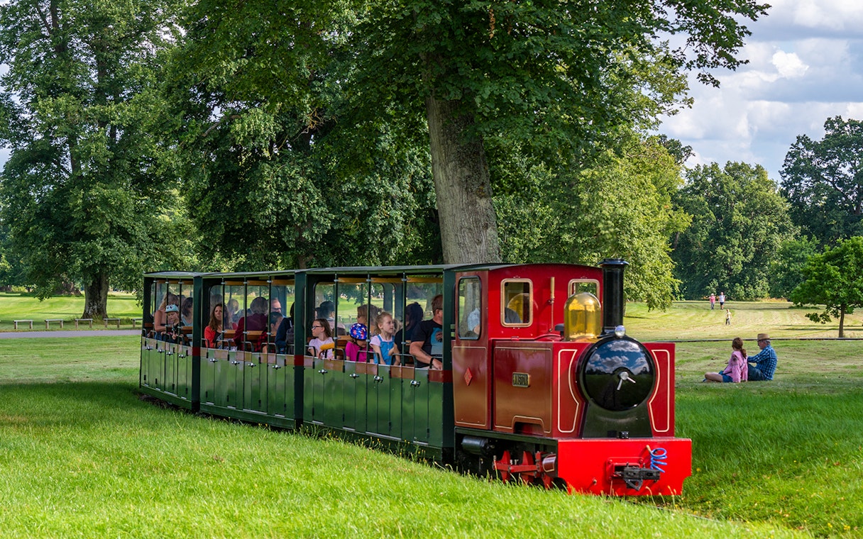 Toy train ride at Blenheim Palace with passengers enjoying the scenic park view.