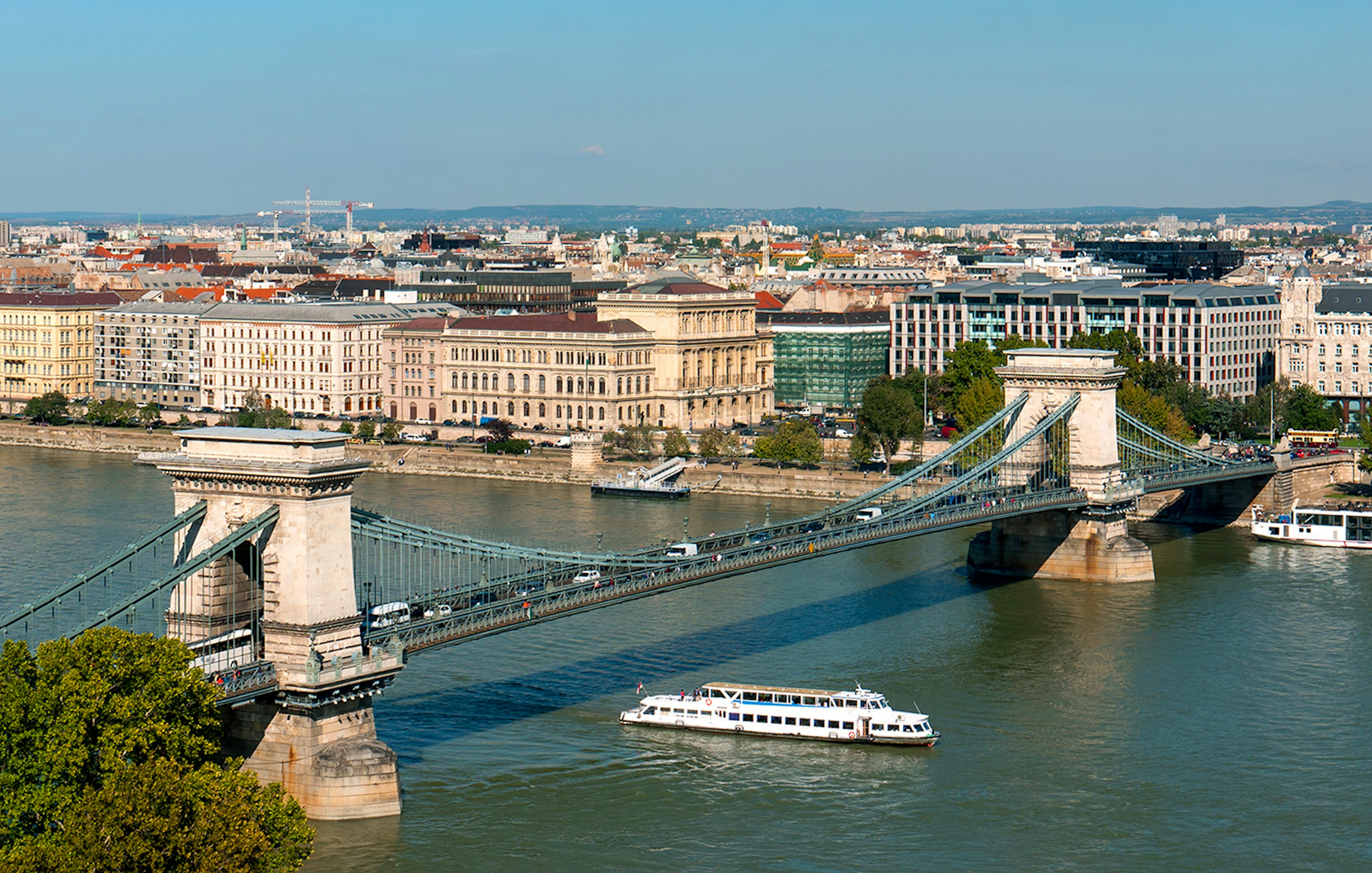 Cruise boat on Danube River passing under Chain Bridge in Budapest.