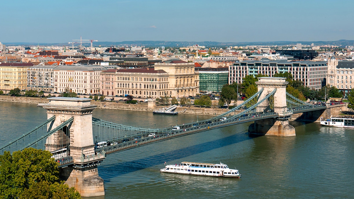 Cruise boat on Danube River passing under Chain Bridge in Budapest.