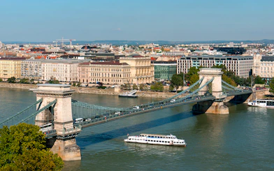 Cruise boat on Danube River passing under Chain Bridge in Budapest.