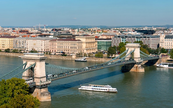 Cruise boat on Danube River passing under Chain Bridge in Budapest.