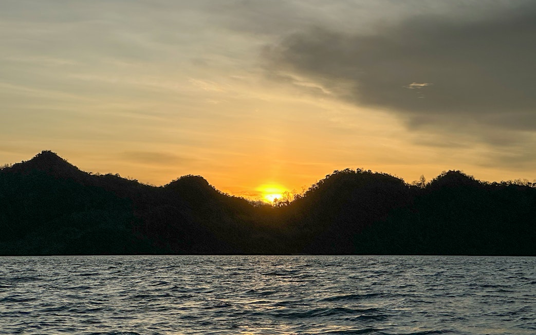 Sunset over water with silhouetted islands during Langkawi mangrove tour.