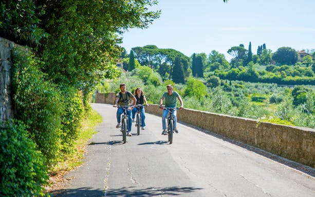 Cyclists on e-bikes riding through Florence hills near Piazzale Michelangelo.