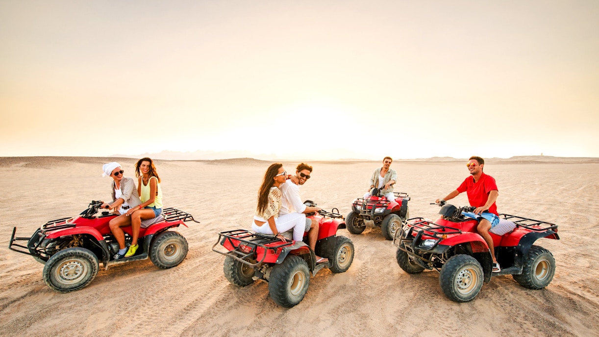 Group riding quad bikes at sunset in the Palmeraie desert.