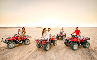 Group riding quad bikes at sunset in the Palmeraie desert.