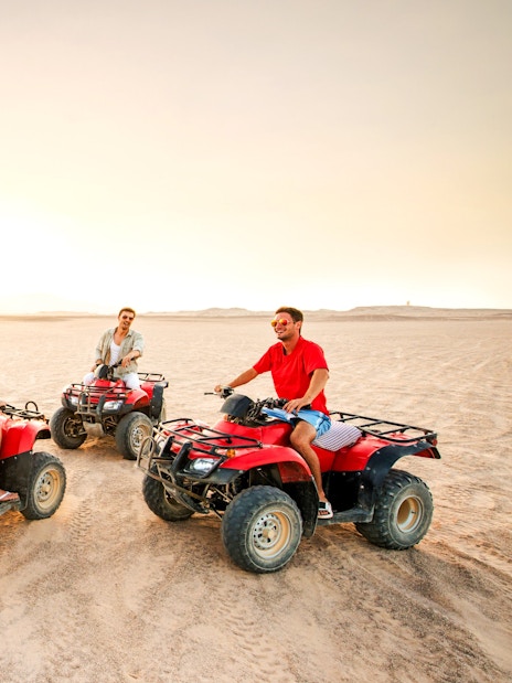 Group riding quad bikes at sunset in the Palmeraie desert.