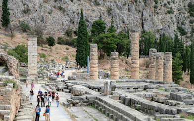 Tourists exploring the ancient ruins of the Temple of Apollo in Delphi, Greece.