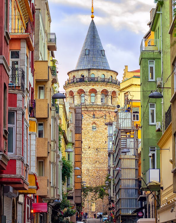 Galata Tower in Istanbul framed by colorful buildings on a narrow street.