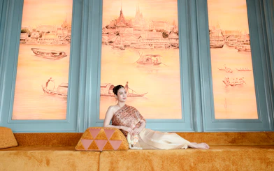 Visitors in traditional Thai costumes at Akara Sky with mural backdrop.