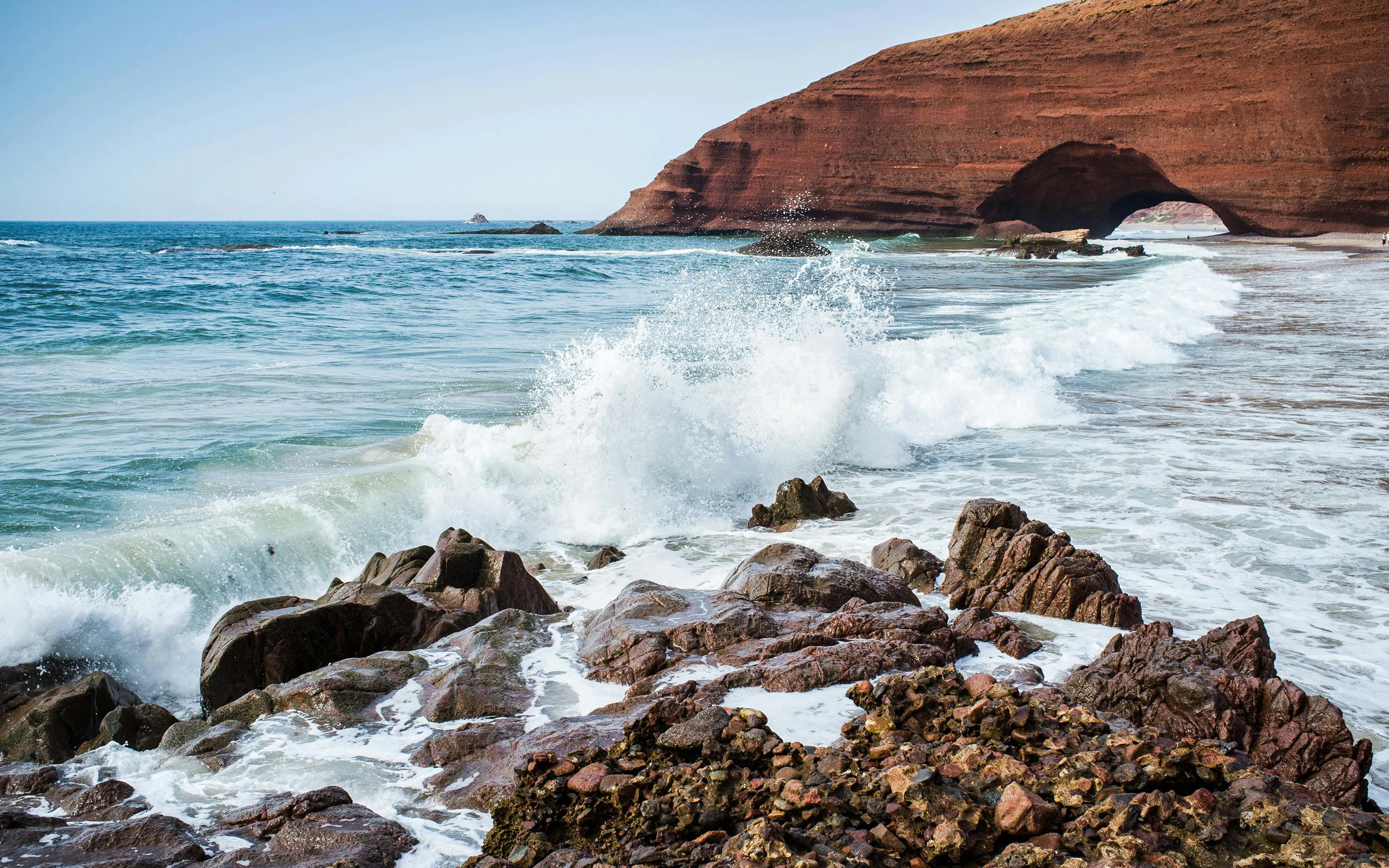 Red rock arch on Legzira Beach with waves crashing, Sidi Ifni, Morocco.