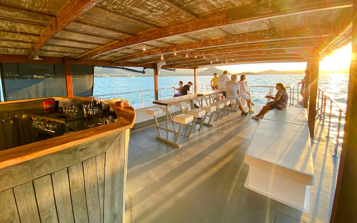 Sundowner cruise bar with people enjoying sunset views at Airlie Beach.